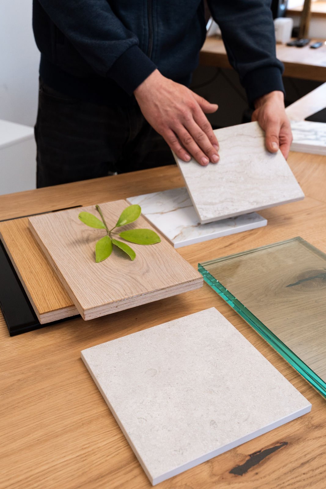 Musterplatten aus Keramik neben Massivholz und Glas, in der Hand geprüft
