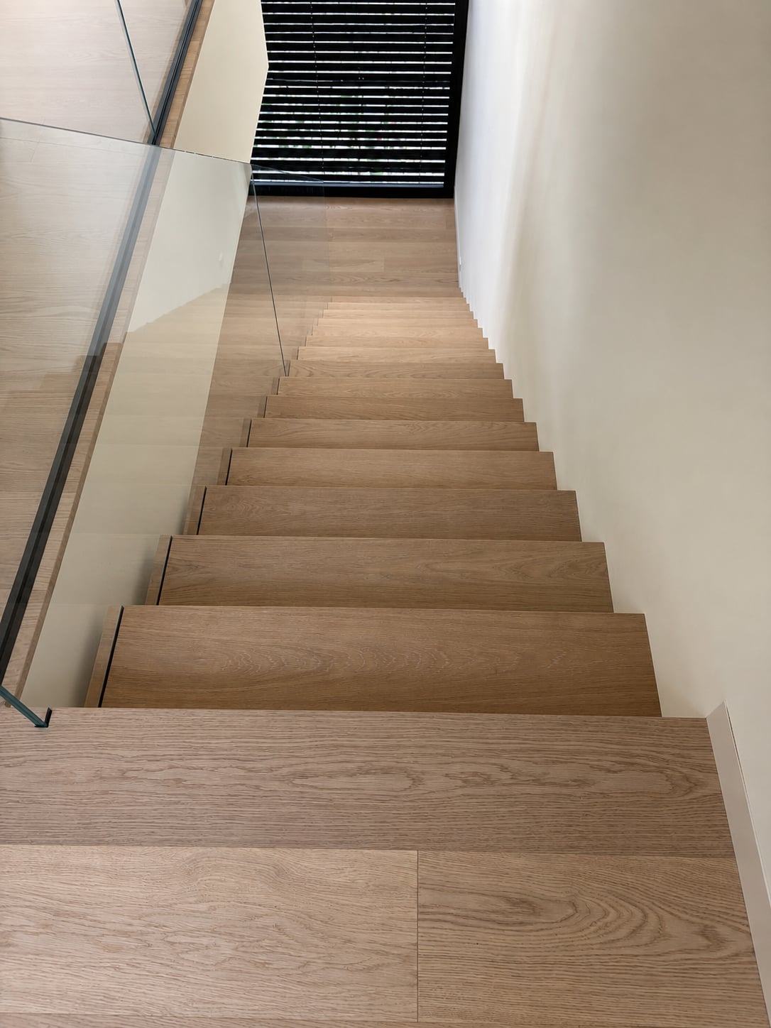 Kragarmtreppe in Eiche mit rahmenlosem Klarglasgeländer im Treppenhaus eines Wohnhauses im Rhein-Main-Gebiet