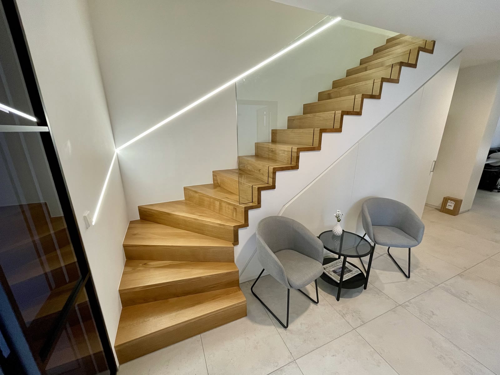 Belegte Betontreppe mit Glasgeländer und Lichtlinie als Beispiel aus der Werkstatt