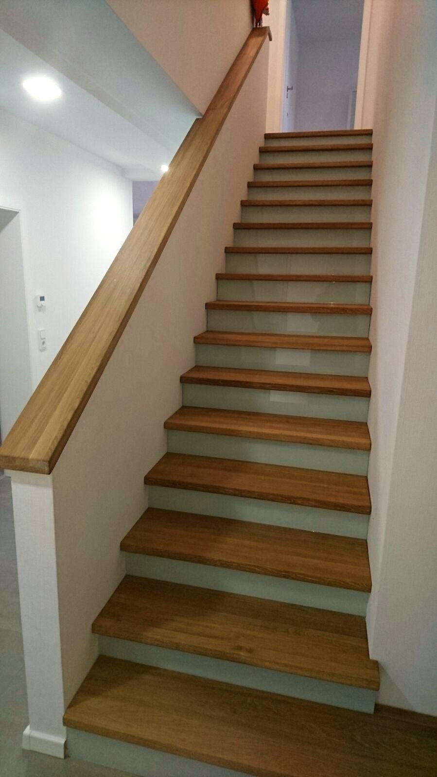 Bestehende Betontreppe mit Eichenstufen belegt, hellen glatten Setzstufen und einem schrägen Handlauf aus Eiche an der Wand