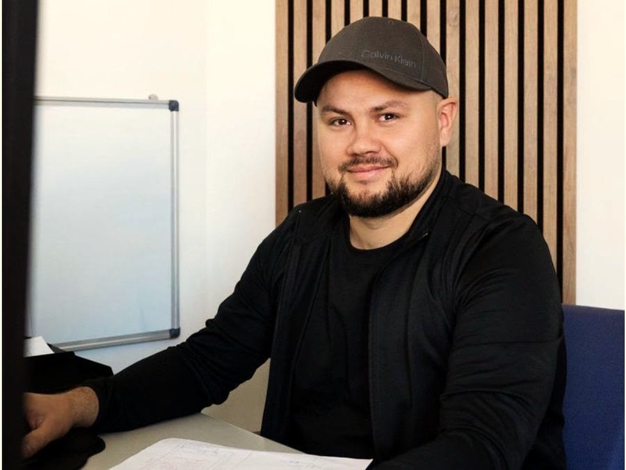 Mitarbeiter im Büro bei der Planung, vor sich die Zeichnung, im Rücken das Whiteboard