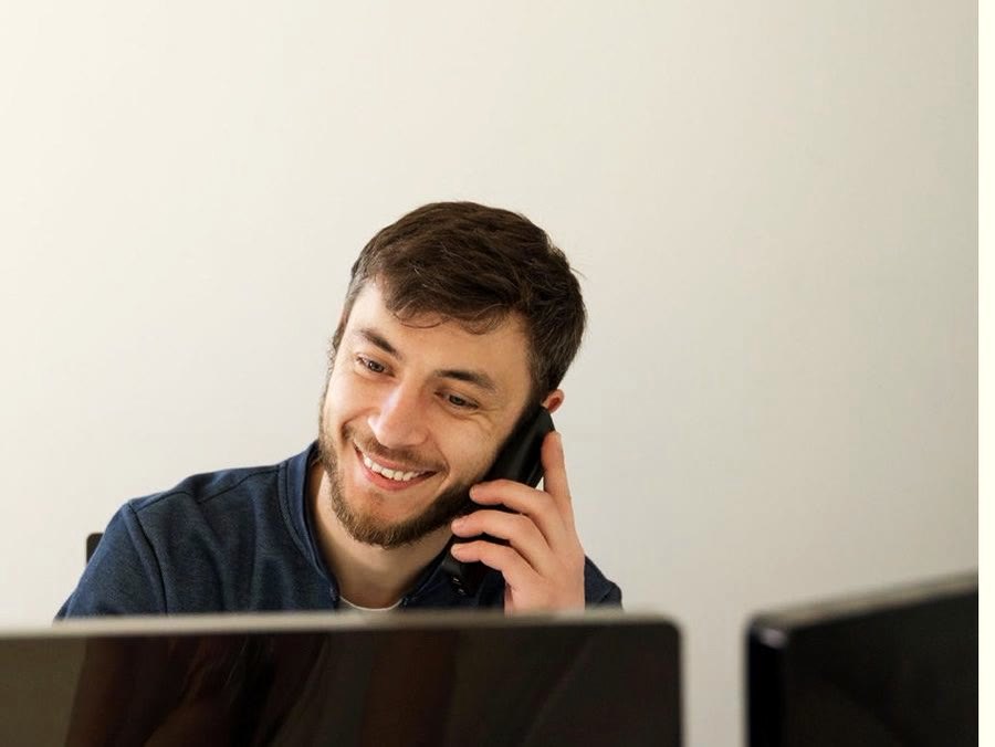 Mitarbeiter am Telefon im Büro vor zwei Bildschirmen