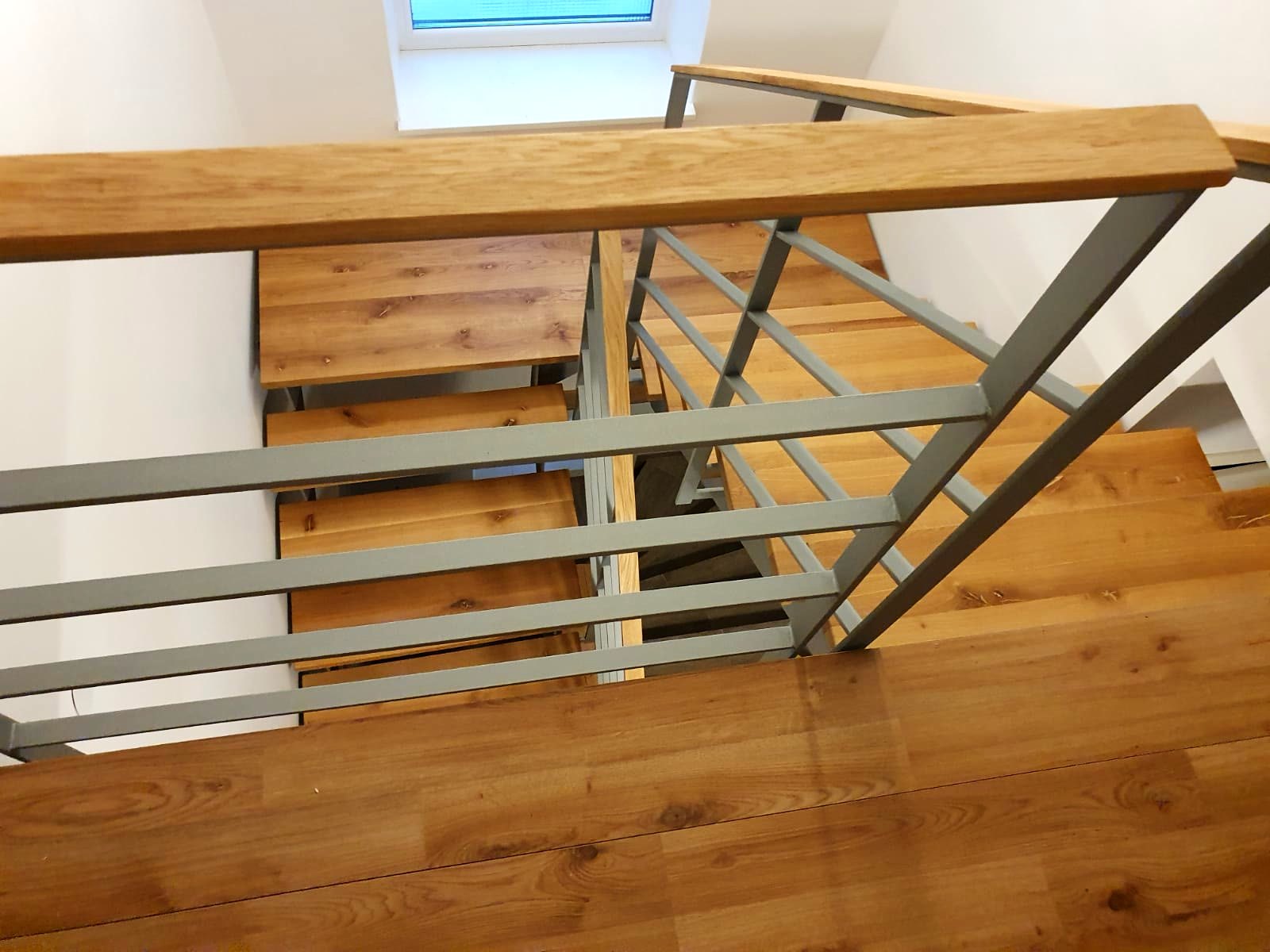 Detail von unten: Stahlwange, aufliegende Holzstufen und Geländerbefestigung
