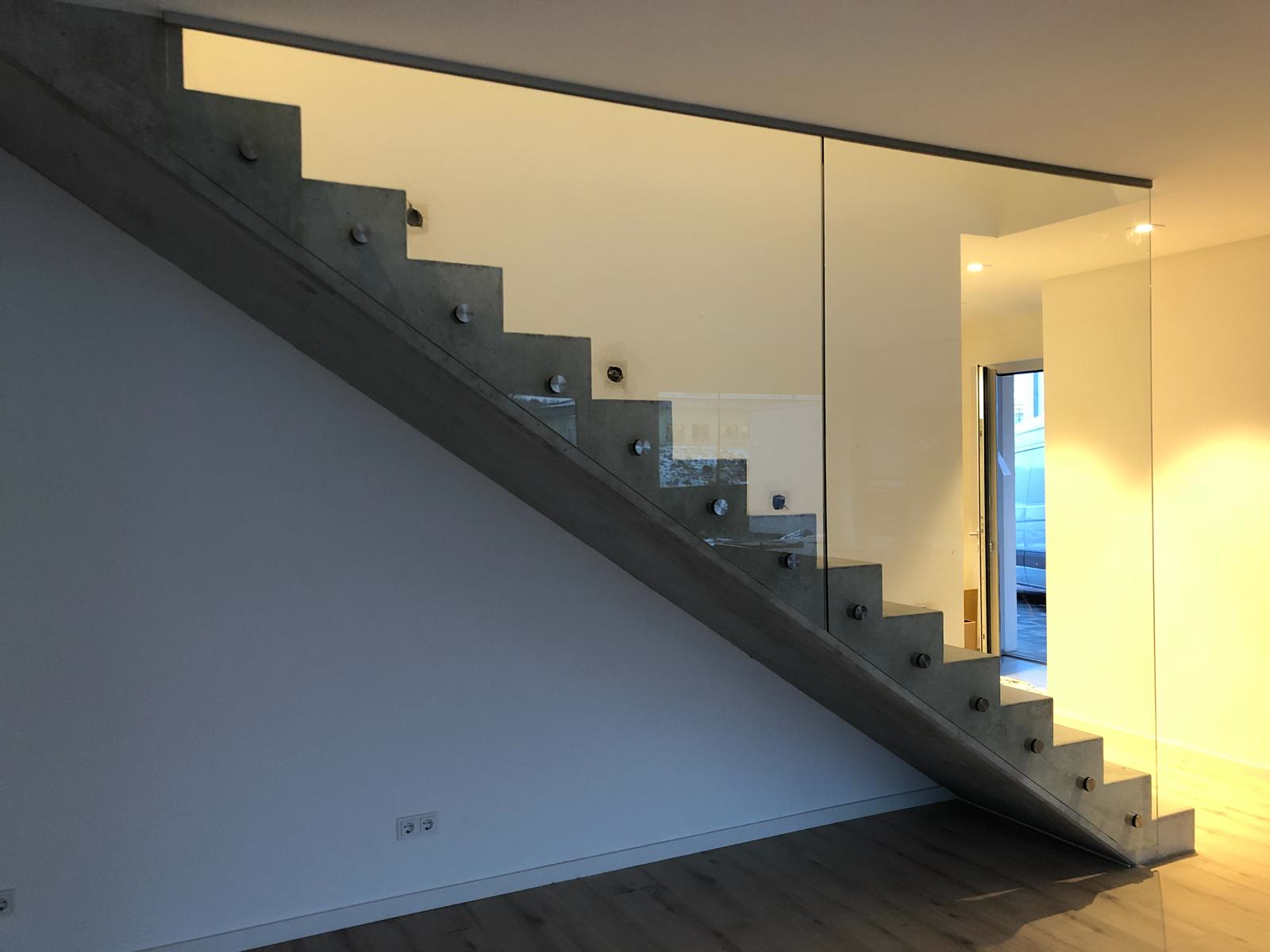 Ganzglasgeländer mit runden Punkthaltern, seitlich an der Wange einer Sichtbetontreppe montiert
